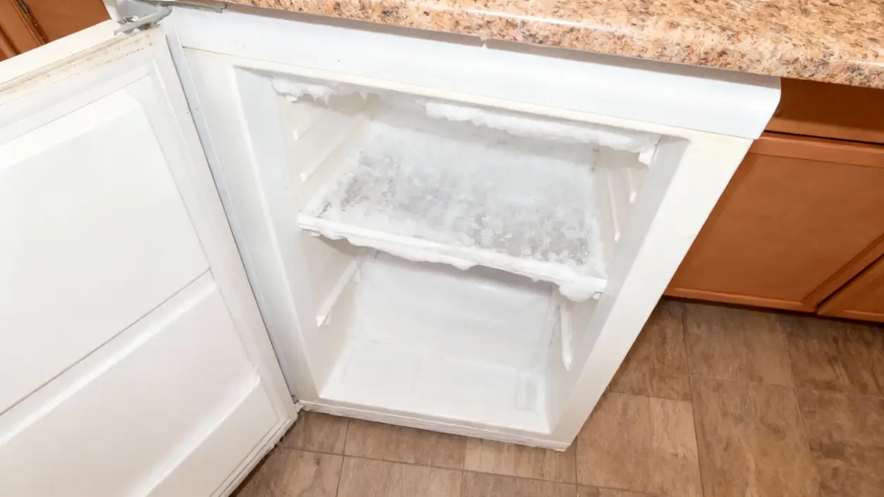 Freezer aperto con abbondante formazione di ghiaccio all'interno