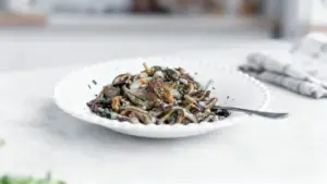 Piatto di funghi trifolati servito in una ciotola bianca con forchetta