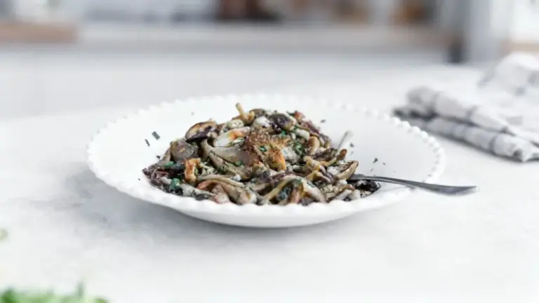 Piatto di funghi trifolati servito in una ciotola bianca con forchetta