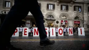 Persone in strada tengono cartelli che formano la parola 'PENSIONI' durante una manifestazione