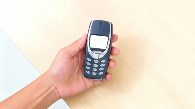 Una mano tiene un vecchio cellulare Nokia su un tavolo chiaro