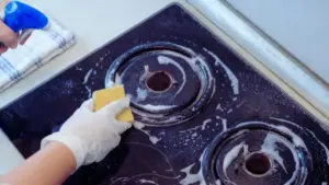 Pulizia di un piano cottura incrostato con una spugna e detergente